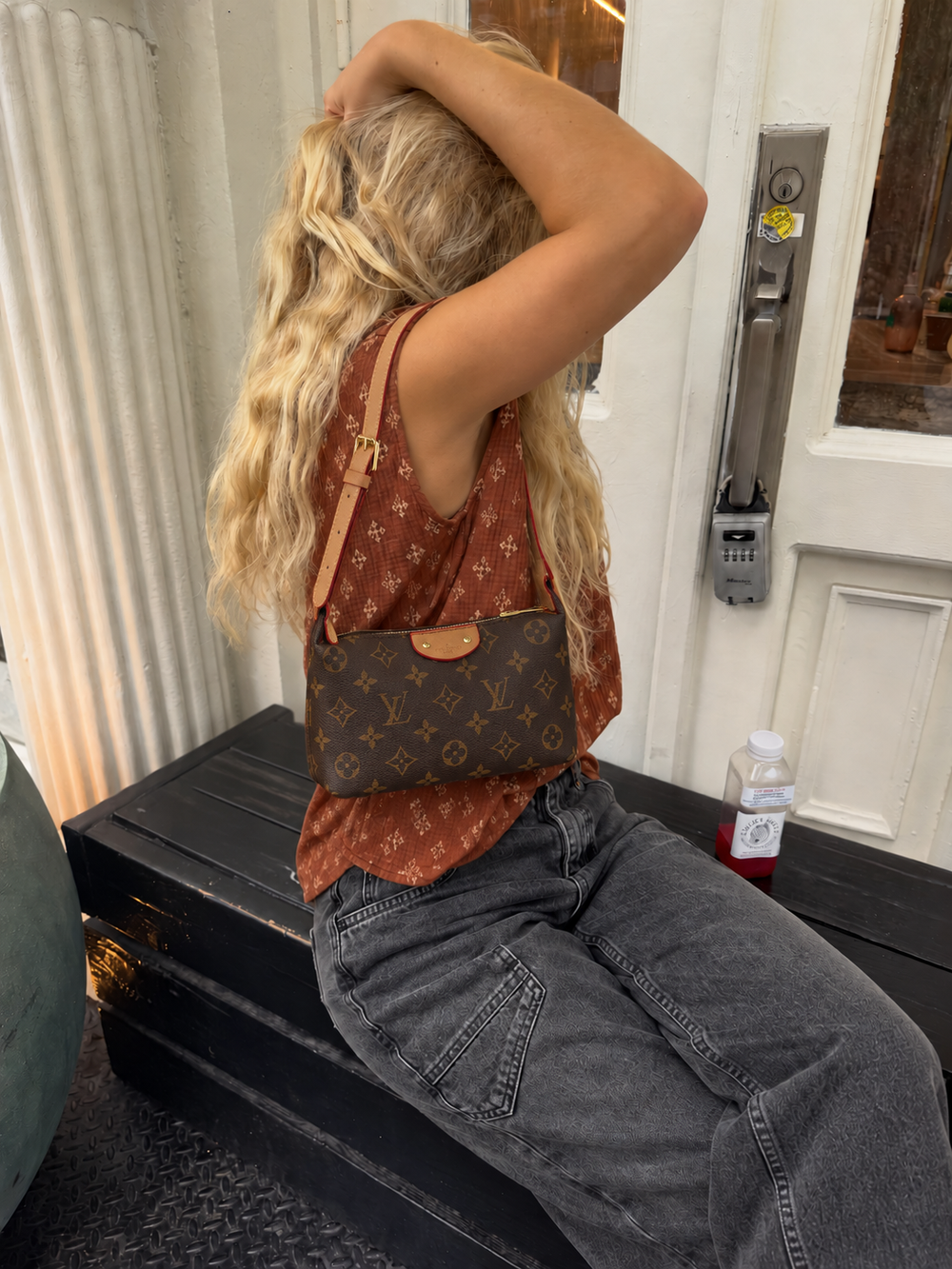 Brown monogram shoulder bag styled with a rust top and jeans