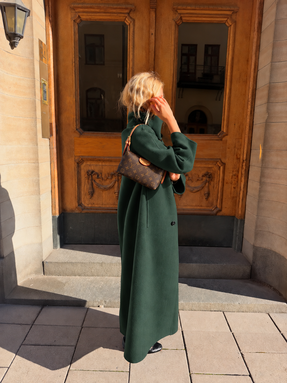 Brown monogram shoulder bag styled with a green coat
