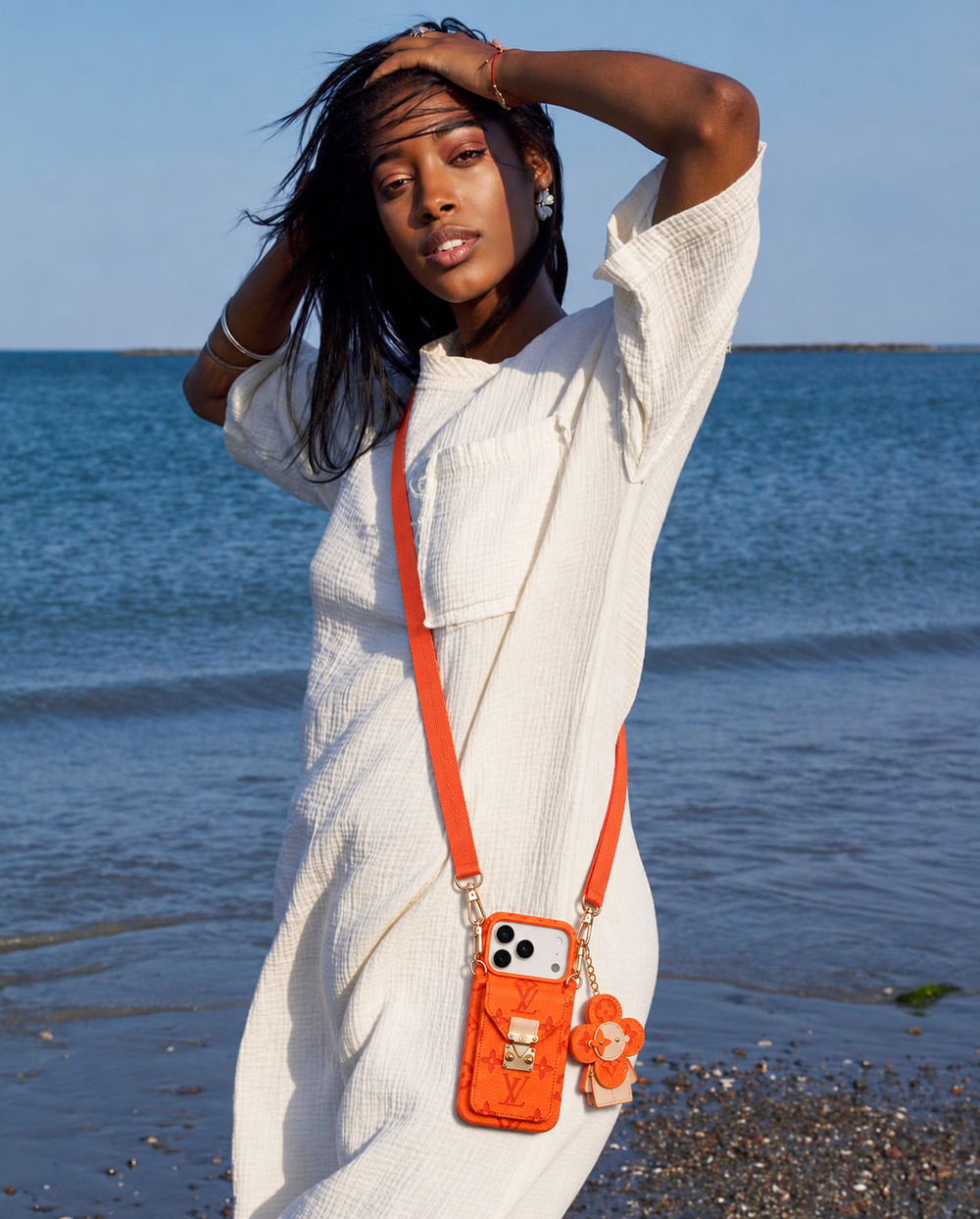 Orange monogram crossbody iPhone case with pocket and flower charm, lifestyle scene 6