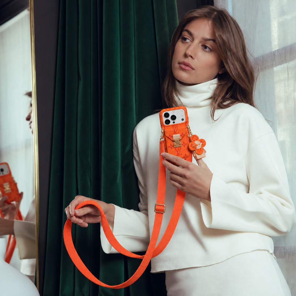 Orange monogram crossbody iPhone case with pocket and flower charm, lifestyle scene 10